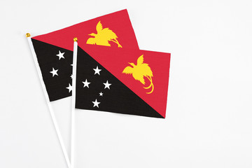 Papua New Guinea and Papua New Guinea stick flags on white background. High quality fabric, miniature national flag. Peaceful global concept.White floor for copy space.