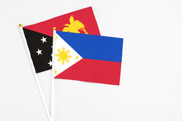 Philippines and Papua New Guinea stick flags on white background. High quality fabric, miniature national flag. Peaceful global concept.White floor for copy space.