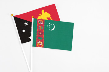 Turkmenistan and Papua New Guinea stick flags on white background. High quality fabric, miniature national flag. Peaceful global concept.White floor for copy space.