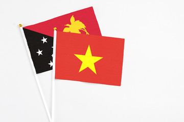 Vietnam and Papua New Guinea stick flags on white background. High quality fabric, miniature national flag. Peaceful global concept.White floor for copy space.