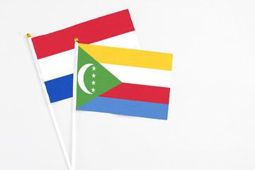 Comoros and Paraguay stick flags on white background. High quality fabric, miniature national flag. Peaceful global concept.White floor for copy space.