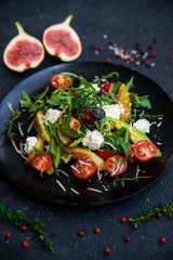 Healthy vegetarian dinner. Bowl with fresh salad, tomatoes avocado, arugula, figs, grapes, feta cheese, rose pepper, olives, roasted vegetables. Superfood, clean eating, vegan, dieting food concept.