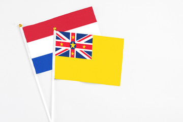 Niue and Paraguay stick flags on white background. High quality fabric, miniature national flag. Peaceful global concept.White floor for copy space.