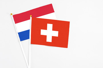 Obraz premium Switzerland and Paraguay stick flags on white background. High quality fabric, miniature national flag. Peaceful global concept.White floor for copy space.