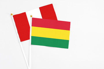 Bolivia and Peru stick flags on white background. High quality fabric, miniature national flag. Peaceful global concept.White floor for copy space.