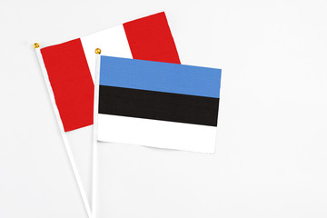 Estonia and Peru stick flags on white background. High quality fabric, miniature national flag. Peaceful global concept.White floor for copy space.