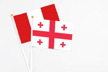 Georgia and Peru stick flags on white background. High quality fabric, miniature national flag. Peaceful global concept.White floor for copy space.