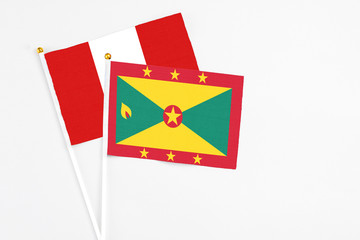Grenada and Peru stick flags on white background. High quality fabric, miniature national flag. Peaceful global concept.White floor for copy space.
