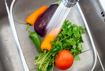 Washing vegetables under the stream of water close-up