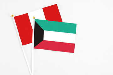 Kuwait and Peru stick flags on white background. High quality fabric, miniature national flag. Peaceful global concept.White floor for copy space.