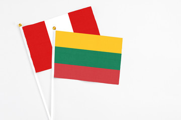 Lithuania and Peru stick flags on white background. High quality fabric, miniature national flag. Peaceful global concept.White floor for copy space.