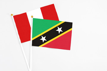 Saint Kitts And Nevis and Peru stick flags on white background. High quality fabric, miniature national flag. Peaceful global concept.White floor for copy space.