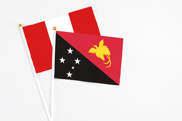 Papua New Guinea and Peru stick flags on white background. High quality fabric, miniature national flag. Peaceful global concept.White floor for copy space.