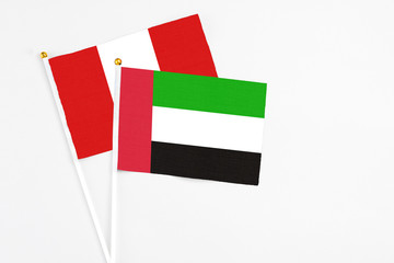 United Arab Emirates and Peru stick flags on white background. High quality fabric, miniature national flag. Peaceful global concept.White floor for copy space.