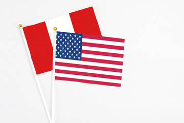 United States and Peru stick flags on white background. High quality fabric, miniature national flag. Peaceful global concept.White floor for copy space.