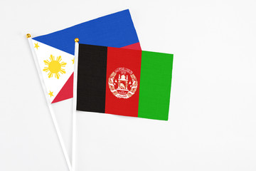 Afghanistan and Philippines stick flags on white background. High quality fabric, miniature national flag. Peaceful global concept.White floor for copy space.