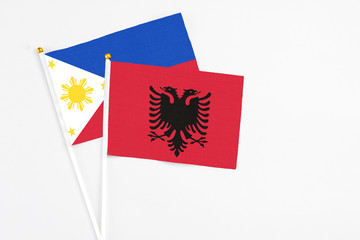 Albania and Philippines stick flags on white background. High quality fabric, miniature national flag. Peaceful global concept.White floor for copy space.