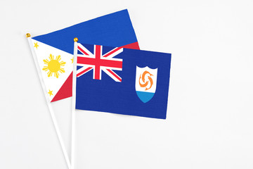 Fototapeta premium Anguilla and Philippines stick flags on white background. High quality fabric, miniature national flag. Peaceful global concept.White floor for copy space.