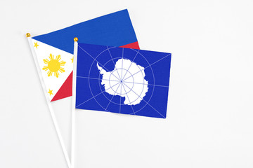 Antarctica and Philippines stick flags on white background. High quality fabric, miniature national flag. Peaceful global concept.White floor for copy space.