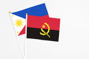 Angola and Philippines stick flags on white background. High quality fabric, miniature national flag. Peaceful global concept.White floor for copy space.