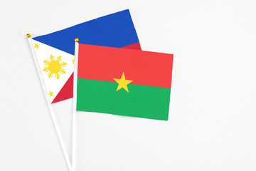 Burkina Faso and Philippines stick flags on white background. High quality fabric, miniature national flag. Peaceful global concept.White floor for copy space.