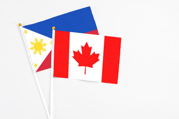 Canada and Philippines stick flags on white background. High quality fabric, miniature national flag. Peaceful global concept.White floor for copy space.