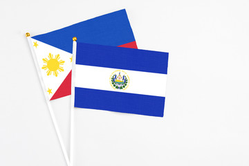 El Salvador and Philippines stick flags on white background. High quality fabric, miniature national flag. Peaceful global concept.White floor for copy space.