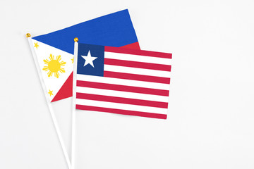 Liberia and Philippines stick flags on white background. High quality fabric, miniature national flag. Peaceful global concept.White floor for copy space.