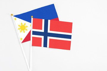 Norway and Philippines stick flags on white background. High quality fabric, miniature national flag. Peaceful global concept.White floor for copy space.