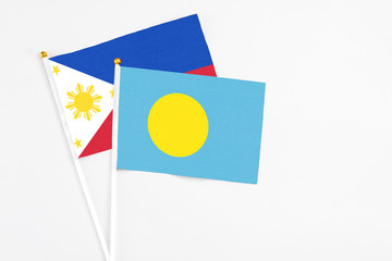 Palau and Philippines stick flags on white background. High quality fabric, miniature national flag. Peaceful global concept.White floor for copy space.