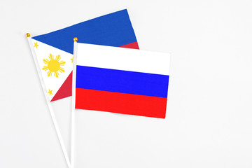 Russia and Philippines stick flags on white background. High quality fabric, miniature national flag. Peaceful global concept.White floor for copy space.