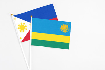 Rwanda and Philippines stick flags on white background. High quality fabric, miniature national flag. Peaceful global concept.White floor for copy space.