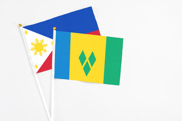 Saint Vincent And The Grenadines and Philippines stick flags on white background. High quality fabric, miniature national flag. Peaceful global concept.White floor for copy space.