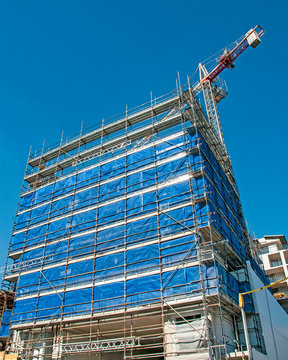 A working Construction crane on top of a highrise building with a blue sky background. Australia.