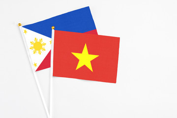 Vietnam and Philippines stick flags on white background. High quality fabric, miniature national flag. Peaceful global concept.White floor for copy space.