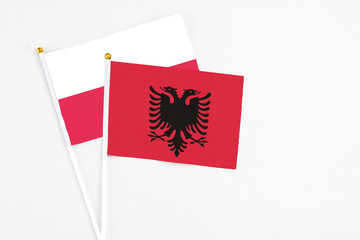 Albania and Poland stick flags on white background. High quality fabric, miniature national flag. Peaceful global concept.White floor for copy space.
