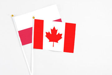 Fototapeta na wymiar Canada and Poland stick flags on white background. High quality fabric, miniature national flag. Peaceful global concept.White floor for copy space.