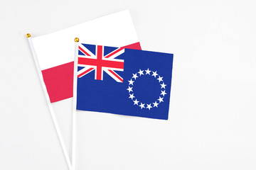 Fototapeta premium Cook Islands and Poland stick flags on white background. High quality fabric, miniature national flag. Peaceful global concept.White floor for copy space.