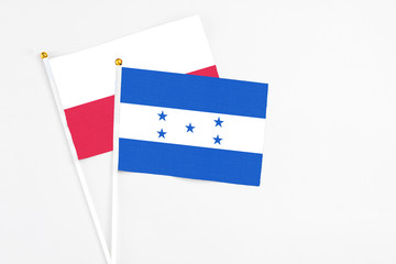 Honduras and Poland stick flags on white background. High quality fabric, miniature national flag. Peaceful global concept.White floor for copy space.