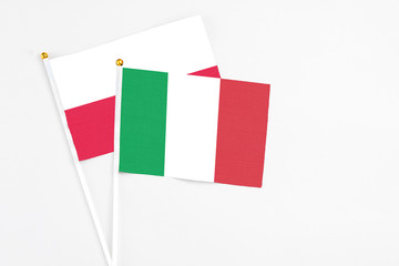 Fototapeta premium Italy and Poland stick flags on white background. High quality fabric, miniature national flag. Peaceful global concept.White floor for copy space.