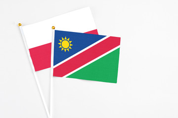 Namibia and Poland stick flags on white background. High quality fabric, miniature national flag. Peaceful global concept.White floor for copy space.