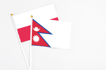 Nepal and Poland stick flags on white background. High quality fabric, miniature national flag. Peaceful global concept.White floor for copy space.