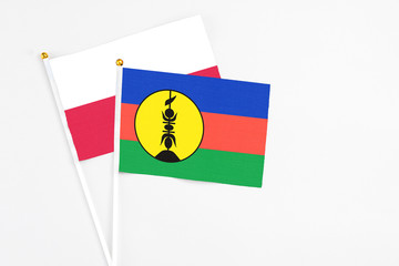 New Caledonia and Poland stick flags on white background. High quality fabric, miniature national flag. Peaceful global concept.White floor for copy space.