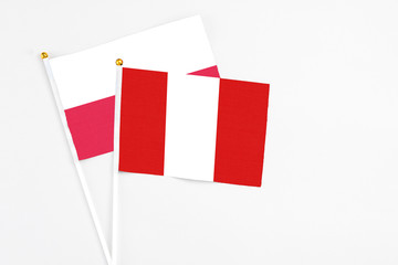 Peru and Poland stick flags on white background. High quality fabric, miniature national flag. Peaceful global concept.White floor for copy space.