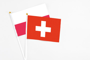 Obraz premium Switzerland and Poland stick flags on white background. High quality fabric, miniature national flag. Peaceful global concept.White floor for copy space.