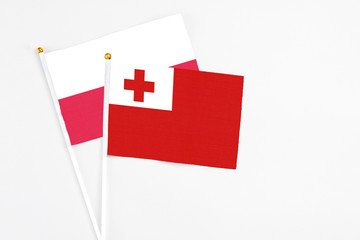 Tonga and Poland stick flags on white background. High quality fabric, miniature national flag. Peaceful global concept.White floor for copy space.