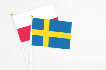 Sweden and Poland stick flags on white background. High quality fabric, miniature national flag. Peaceful global concept.White floor for copy space.