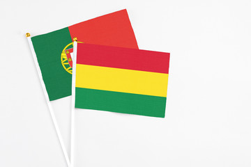 Bolivia and Portugal stick flags on white background. High quality fabric, miniature national flag. Peaceful global concept.White floor for copy space.