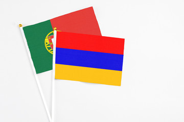 Armenia and Portugal stick flags on white background. High quality fabric, miniature national flag. Peaceful global concept.White floor for copy space.