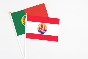 French Polynesia and Portugal stick flags on white background. High quality fabric, miniature national flag. Peaceful global concept.White floor for copy space.